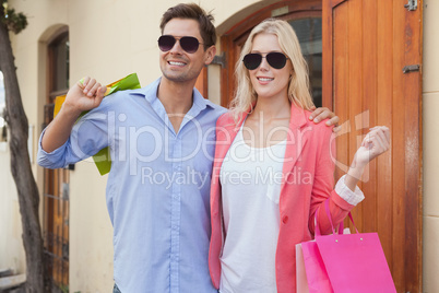 Stylish young couple standing with shopping bags