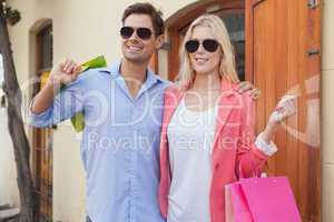 Stylish young couple standing with shopping bags