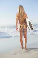 Gorgeous blonde surfer in bikini holding her board