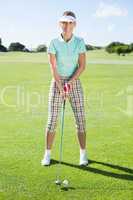 Lady golfer teeing off for the day smiling at camera