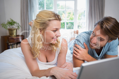 Cute couple relaxing on bed using the laptop