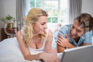 Cute couple relaxing on bed using the laptop