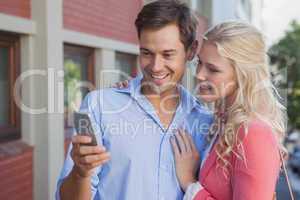 Stylish young couple looking at smartphone