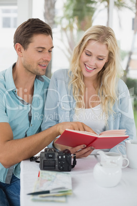 Cute hipster couple reading book together at table