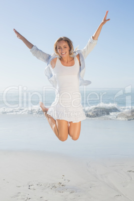 Smiling blonde leaping by the sea