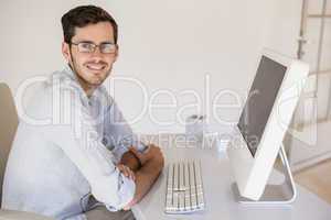 Casual businessman sitting at his desk smiling at camera