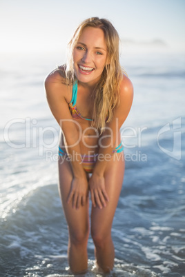 Happy blonde smiling at camera in bikini at the beach