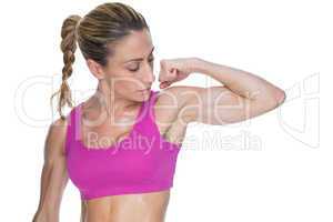 Female bodybuilder flexing bicep in pink sports bra