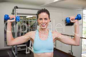 Smiling woman lifting blue dumbbells