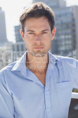 Handsome man frowning at camera on his balcony