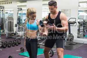 Personal trainer coaching female bodybuilder lifting dumbbell