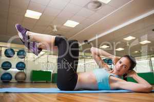 Fit brunette doing sit ups in fitness studio