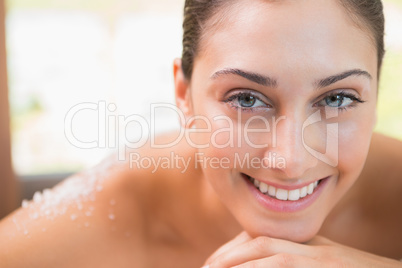 Beautiful smiling brunette lying on massage table with salt scru