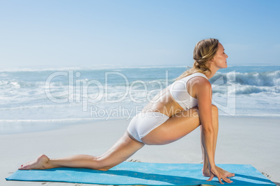Gorgeous fit blonde in lunging yoga pose on the beach