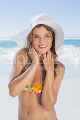 Beautiful girl in white straw hat smiling at camera on beach