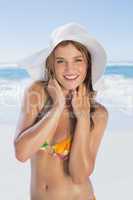Beautiful girl in white straw hat smiling at camera on beach