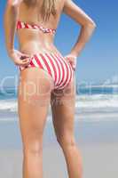 Mid section rear view of fit woman in striped bikini at beach