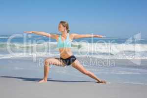 Fit woman standing on the beach in warrior pose