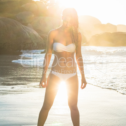 Beautiful blonde in white bikini at the beach with wet hair