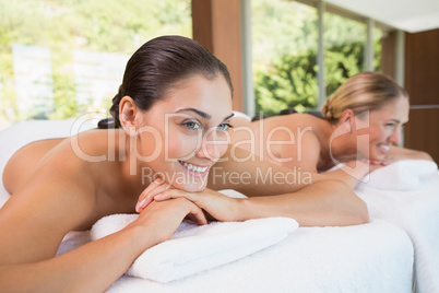 Happy friends lying on massage tables with hot stones on their b