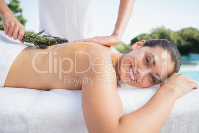 Smiling brunette getting an aromatherapy treatment poolside