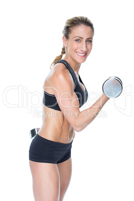 Female bodybuilder working out with large dumbbells smiling at c