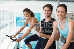 Fit women in a spin class with trainer taking notes and smiling
