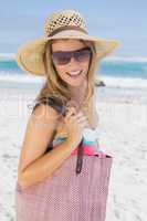 Beautiful laughing blonde on the beach holding bag