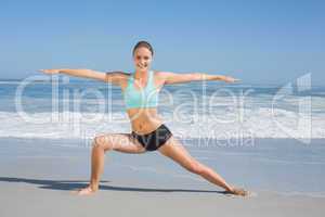 Fit woman standing on the beach in warrior pose