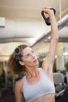 Fit woman lifting up kettlebell