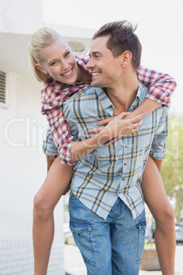 Young hip man giving his blonde girlfriend a piggy back