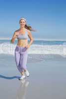 Sporty smiling blonde jogging on the beach