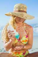 Woman sitting on the beach applying suncream