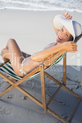 Smiling woman relaxing in deck chair on the beach