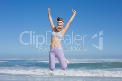 Sporty happy blonde jumping on the beach