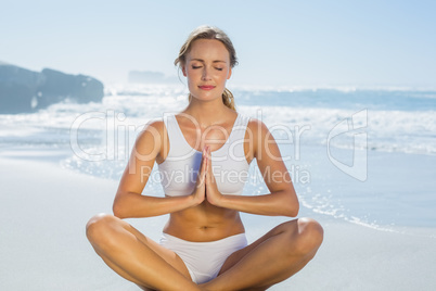 Gorgeous blonde in lotus pose by the sea