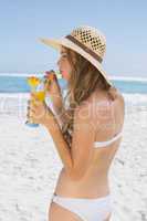 Pretty blonde in bikini holding cocktail on the beach