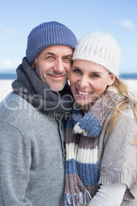 Smiling couple standing on the beach in warm clothing