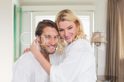 Cute couple in bathrobes smiling at camera