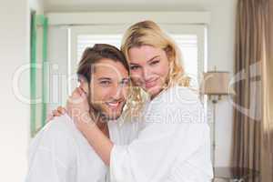 Cute couple in bathrobes smiling at camera