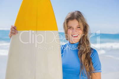 Fit smiling surfer girl on the beach with her surfboard