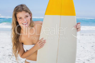 Pretty surfer girl holding her surfboard on the beach