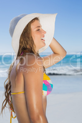 Beautiful girl in bikini and straw hat smiling on beach