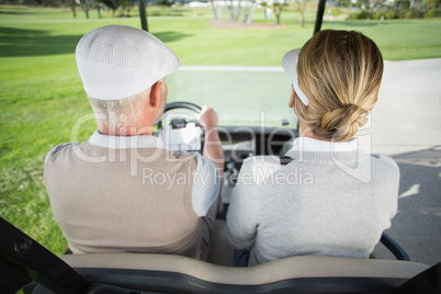 Golfing couple driving in their golf buggy