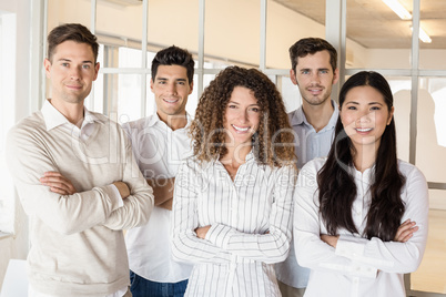 Casual business team smiling at camera with arms crossed