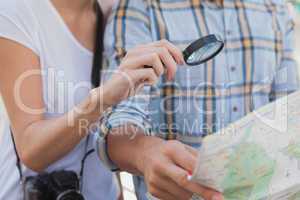 Young tourist couple using magnifying glass on the map