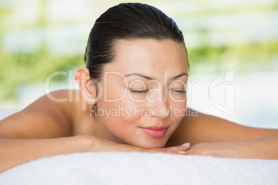 Smiling brunette lying on massage table with eyes closed