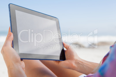 Woman sitting on beach in deck chair using tablet pc Woman sitting on beach in deck chair using tablet pc