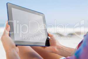 Woman sitting on beach in deck chair using tablet pc