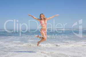 Happy fit woman in bikini jumping on the beach